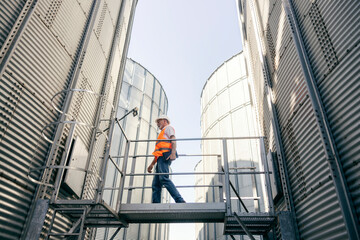 Senior male industry worker walking outdoors at large metallic facility during daytime