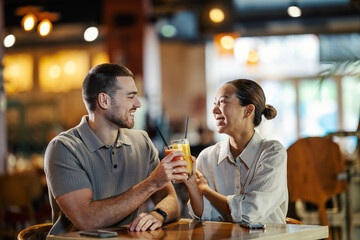 Happy diverse couple toasting drinks on a restaurant date