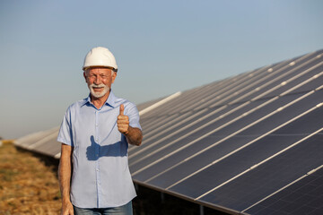 Senior White Male Environmentalist Giving Thumbs Up Near Solar Panels on Sunny Day