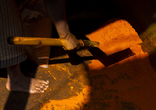 Man picking up turmeric orange powder with a shovel in a mill, Dhaka Division, Dhaka, Bangladesh