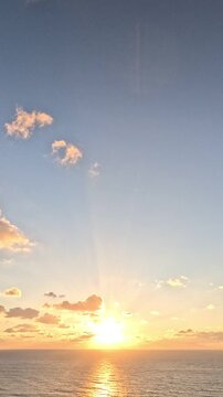 Sunset, ocean, clouds create a beautiful, tranquil, and serene nature landscape with warm sky colors. Vertical video.