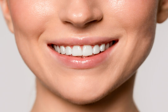 Smiling woman shows her white teeth with natural light in a simple background during a close-up shot