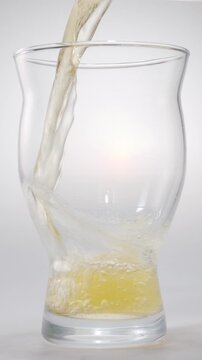Pouring beer into a glass on a white background. Gas bubbles rise, forming foam.