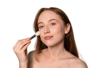 Fototapeta premium Woman applies makeup with a brush at a bright indoor setting during the day