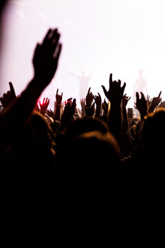 Audience cheering with raised arms at outdoor music festival stage