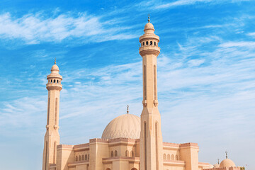 Al Fateh Grand Mosque architecture featuring a dome and tall minarets against a clear blue background
