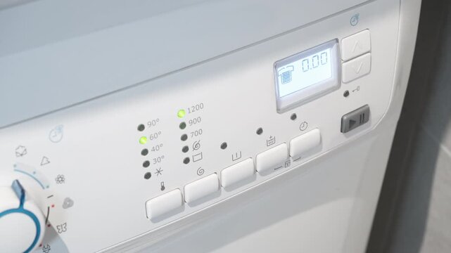 Electronic washing machine panel displays end of program with audible beeping signal. Household appliance finishes cleaning clothes cycle, white laundry equipment with buttons and LED lights.