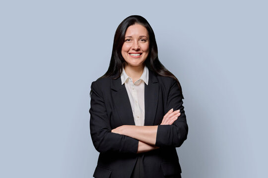 Confident successful middle-aged businesswoman in black jacket on grey studio background