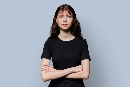 Portrait of smiling confident teenage girl with crossed arms on gray background