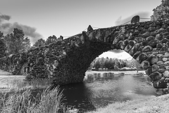 The Boulder Bridge of Vasilevo, Russia. It is a hundred-meter arched bridge with grottoes, made using the archivolt technique. Black and white photo featuring beautifully crafted historic stone bridge