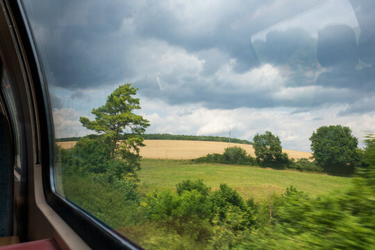 View from train window overlooking agricultural field in motion.