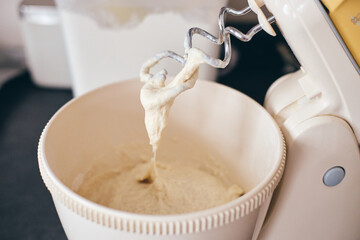 Close-up of stand mixer kneading creamy dough. Smooth texture and mixing process in kitchen setting. Ideal for baking, cooking, culinary content, recipes, food blogs, appliance promotions.
