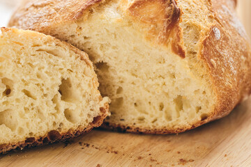 Sliced artisan sourdough bread with airy crumb on wooden board, glass of milk, and knitted cloth. Ideal for culinary, baking, and food photography projects.