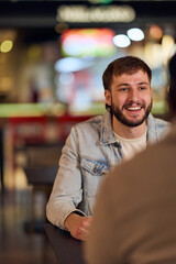 Fototapeta premium Friendly Conversation At A Cafe With A Bearded Man In A Denim Jacket