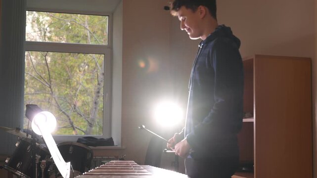 A teenage boy plays a wooden xylophone in class. Drums lesson at a music school.