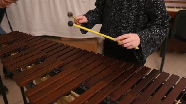 A close-up of a teenager playing a wooden xylophone. Drums lesson at a music school. Closeup no face