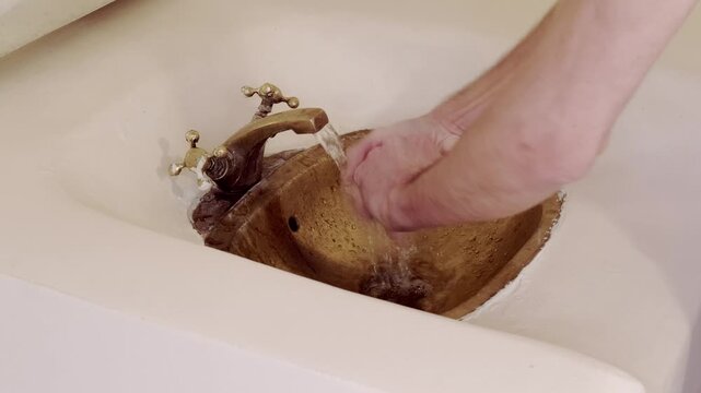 young man washing in Rustic brass sink, morning skincare routine in Moroccan-style interior, Self-care and mindfulness, basic hygiene and cultural touch in Morocco
