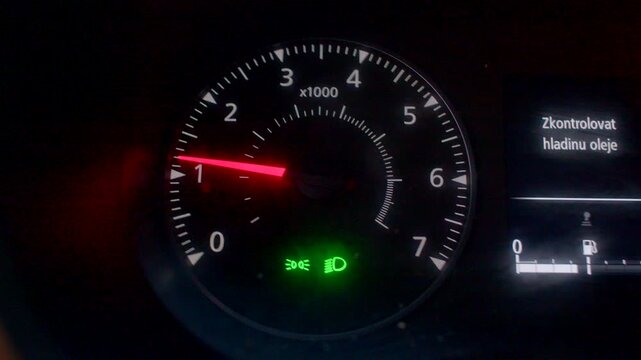 Dashboard gauge details, Car meter with warning signals, Closeup of vehicle instrument cluster features, Detailed view of car dashboard showing RPM gauge and alert icons in low light 