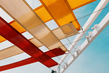 Outdoor architectural shades creating a vibrant overhead canopy, providing shelter from the sun with colorful fabric strips