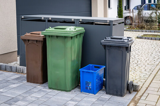 Modern houses in a German residential area with colorful waste sorting bins on a paved street