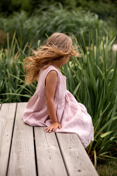 Girl on the bench in pink linen dress, summer vibe, flowing hair