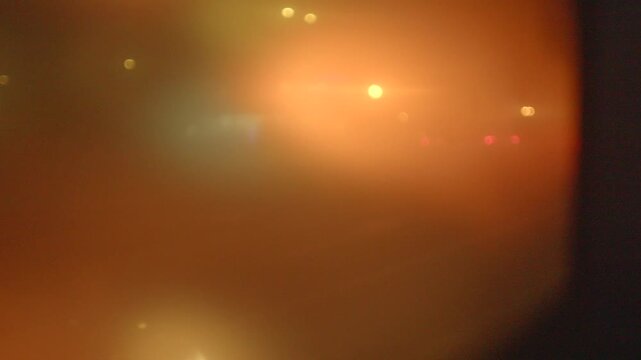 blurred colorful city lights through fogged glass creating bokeh and soft glow, evening traffic colors bleeding into warm palette, abstract urban night mood for cinematic backgrounds