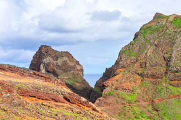 Volcanic cliffs of Ponta de Sao Lourenco on Madeira Island. Rugged trail winds through a colorful, arid landscape under a cloudy sky