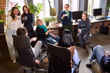 Obraz premium Group of women gathered for team conversation in loft office. Concept of collaborative brainstorming meeting, inclusive workplace environment, strategic planning discussion, professional communication