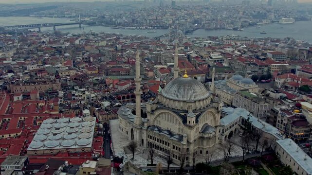 Aerial view centered on the Nuruosmaniye Mosque with the waters of the Golden Horn in the background. The Galata Bridge and Atat&uuml;rk Bridge are visible among dense urban structures and mosques
