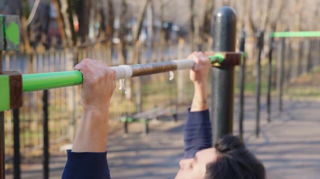 Young man doing pull ups on a bar in an outdoor park