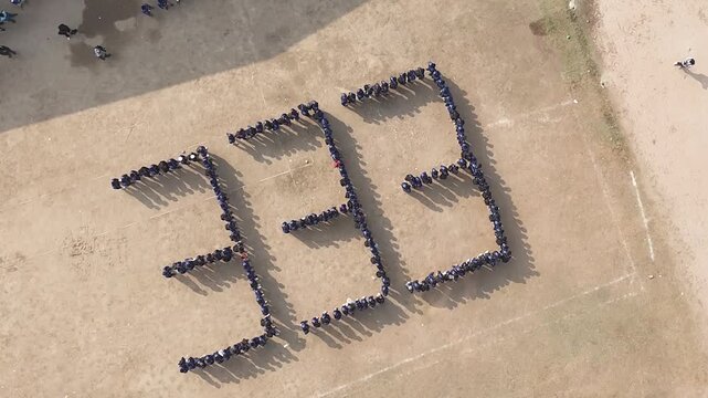Aerial drone footage of students forming the number 333 with their bodies on a dirt field.
