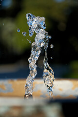 Water Splash from Drinking Fountain on a Sunny Day &ndash; Blurred Background. Dynamic Splash in Public Drinking Fountain under Bright Sun with Bokeh Background