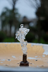 Water Splash from Drinking Fountain in Park &ndash; Blurred Background. Fresh Water Droplets from Resort Drinking Fountain, Shallow Depth of Field