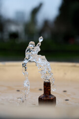 Water Splash from Drinking Fountain in Park &ndash; Blurred Background. Fresh Water Droplets from Resort Drinking Fountain, Shallow Depth of Field