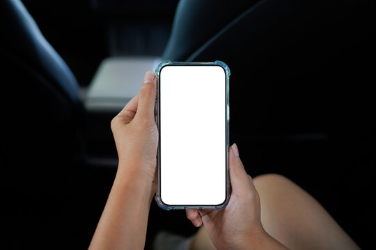 Close up of a woman's hand using a smartphone in the car. Mobile phone white screen display in car for app. Mockup