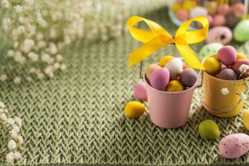Easter holiday background. Mini chocolate egg candies in buckets with gypsophila flowers. Copy space