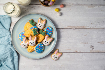 Easter cookies with bottles of milk on white wooden background and mini chocolate easter candy eggs. Spring holidays background