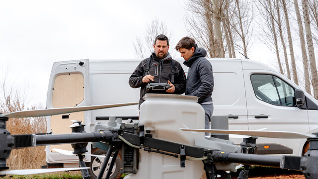 Farmers reviewing drone operation by van