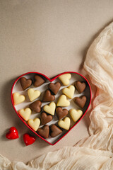 Valentine's Day chocolate candies in red heart shaped box on neutral background. Top view with copy space