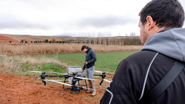Farmers preparing agricultural drone on field