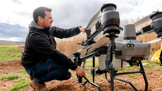 Farmer adjusting agricultural drone for fieldwork