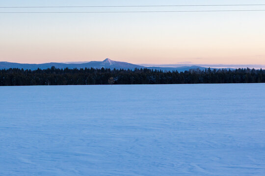 Ural Mountains near the city of Beloretsk, Republic of Bashkortostan. Snow-covered landscape with distant mountains under pastel sky at dawn, serene winter scene in rural area
