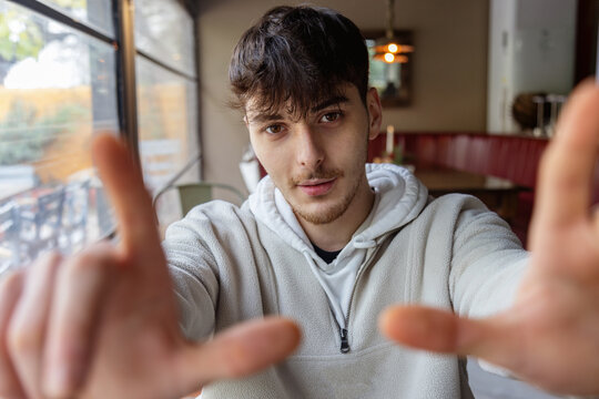 Young man framing a shot with his hands in a cozy cafe