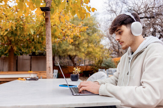 Young man freelancing outdoors with technology