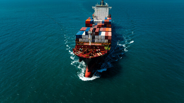 Close up aerial front view of cargo ship cutting through water waves for global business logistics and international import export trade transportation industry.