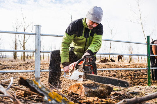Man cutting wood outdoors with a chainsaw