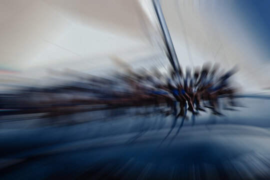 Sailors sitting along the side of a maxi yacht to balance the vessel during a regatta. Zoom burst applied to film scan. Teamwork, discipline, organisation, cohesion concepts.