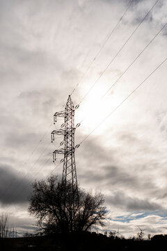 Silhouette of power line tower against cloudy sky