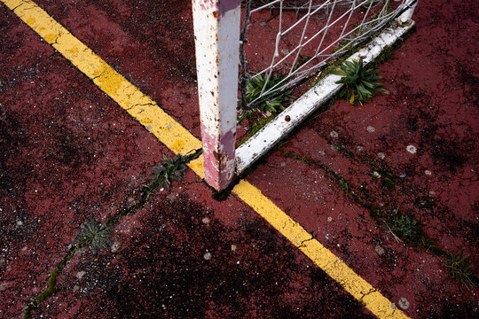 Weathered soccer goalpost on cracked pavement