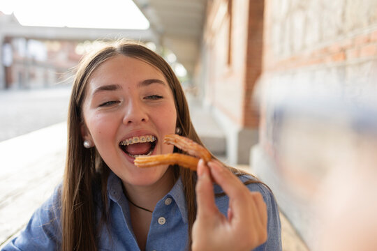Girl joyfully eating churros with braces